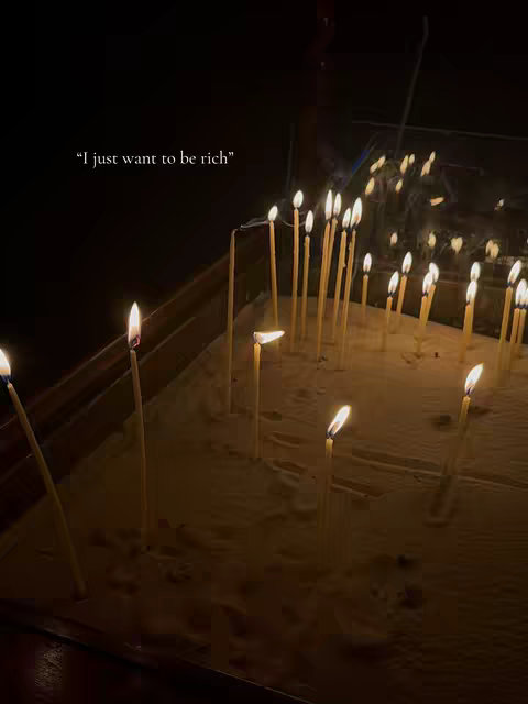 The image shows candles that are tall, thin, and cream-colored. The image is dark with the candles in slight focus, some are lit, there is text, overlaid on the picture.