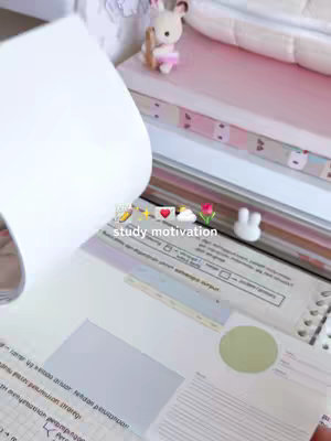 The image features an open notebook with handwritten notes, a stack of colorful books in the background. A small teddy bear is perched on the books. The text overlayed reads 'study motivation' with some emojis.