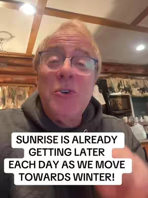 A man with glasses is centered in the frame, looking directly at the camera and speaking. The background is filled with wooden paneling and a ceiling with recessed lights. Overlaying the image is text that says 'SUNRISE IS ALREADY GETTING LATER EACH DAY AS WE MOVE TOWARDS WINTER!'