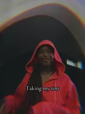 A person wearing a red hoodie is the central element, standing in front of a blurred background. The person is looking at the camera and has dark hair. Text overlayed at the bottom reads "Taking my sins". A rainbow effect is visible in the top portion of the image.