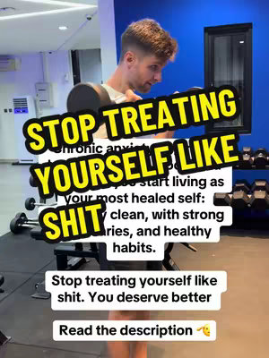 A man is lifting weights in a gym, with a text overlay in the foreground that says "STOP TREATING YOURSELF LIKE SHIT". The words are in a bold, yellow and black banner that spans across the image. The man is wearing workout attire and the background shows gym equipment, blue wall, and a window with the bright lighting.
