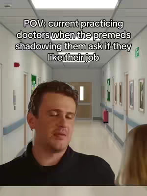 The cover image presents a man in the foreground, slightly off-center, positioned in what appears to be a brightly lit hospital hallway. The background shows a long corridor with doors on both sides, suggesting a medical setting. Text overlayed at the top reads, POV: current practicing doctors when the premeds shadowing them ask if they like their job'. The image is professionally lit with a focus on the man, his expression is a neutral, contemplative look.