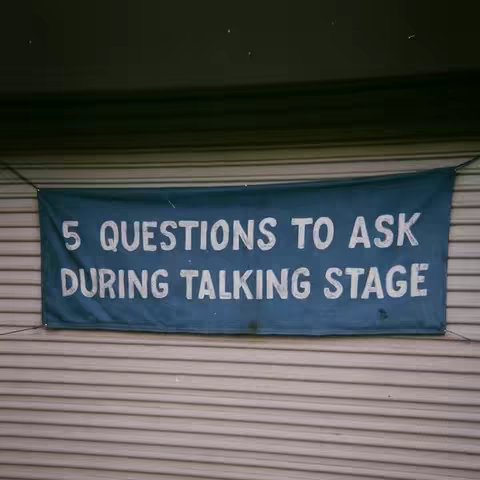 A banner with the text '5 QUESTIONS TO ASK DURING TALKING STAGE' is displayed against a background of horizontal, light brown siding. The banner is a dark teal color and has white text.