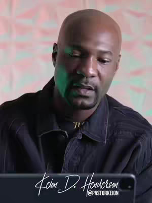 The cover image is a medium shot of a Black man with a shaved head, looking down with a contemplative expression. The background appears to be a mix of pink and soft lighting. The man is wearing a black collared shirt with a gold chain. In the bottom portion of the image is a signature that identifies him as "Keion D. Henderson", and his Instagram handle below.
