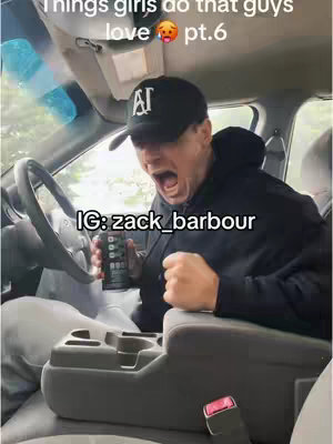 The image is a selfie taken inside a car. The main subject is a man wearing a black baseball cap with the letters "AI" on it, a black hoodie, and is mid-scream, seeming surprised or shocked. He holds a can with text on it. The car interior is visible, with the steering wheel and dashboard also visible. The primary color of the image is black and gray.