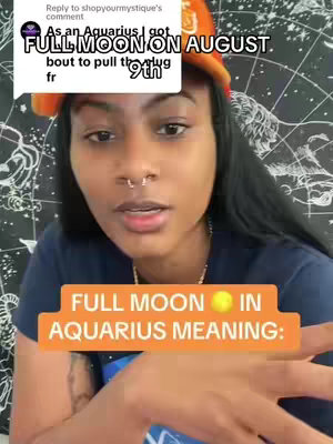 The image is a selfie-style video cover featuring a young woman. She has dark hair, a nose ring, and is wearing a dark top under what appears to be an orange cap or hat. The background shows various symbols, possibly related to astrology. Overlayed on the image are text blocks, one with the caption 'FULL MOON IN AQUARIUS MEANING:' appearing in an orange bar. Additional overlaid text is visible in a comment section, providing context for the video. The overall composition is direct, with the woman as the central focus and the overlaid text providing informational content.