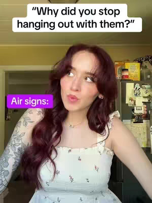 A woman with long auburn hair is looking up slightly, with a gentle smile. She is wearing a white top with floral patterns and has a tattoo on one arm. Above her, a text box contains a statement, while a purple box with the words "Air signs:" is placed near the bottom left.
