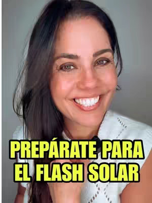 A smiling woman with long dark hair is the focal point. She wears a white top. Bold, yellow text with a black outline overlays the image, reading 'PREPÁRATE PARA EL FLASH SOLAR'. The background is blurred and neutral in color, placing emphasis on the woman and text.