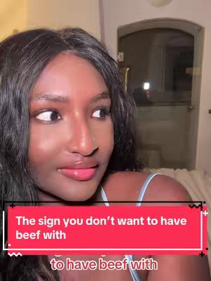 A medium shot featuring a woman with dark hair angled slightly, looking off to the right. She has dark skin, and is wearing a light blue top. Overlayed on the bottom is a red banner with white text that reads: The sign you don’t want to have beef with, and more white text below it that is partially cropped. The background is somewhat blurry, offering a glimpse of an indoor setting with a window.