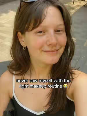 A selfie-style image featuring a woman with brown hair smiling slightly. She is wearing a black top with a white trim. Sunglasses are placed on top of her head. Text overlayed at the bottom of the image.