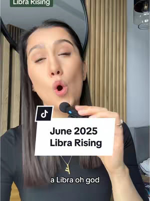 A woman is holding a microphone and looking directly into the camera with a slightly open mouth. She has dark hair and is wearing a black top and gold necklace, there is a white text box overlayed on the image that says 'June 2025 Libra Rising'.
