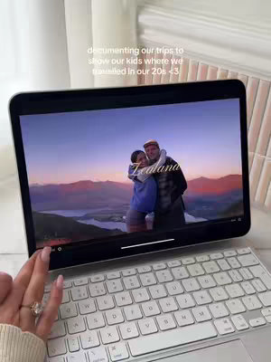 The cover image shows a woman holding a tablet displaying a video of her and a man embracing in front of a scenic mountain backdrop. The tablet rests on a keyboard and some background elements, including a stack of books.