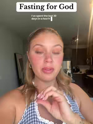 A woman is centered in a selfie-style video, with a light-skinned complexion, blonde hair, and rosy cheeks. Text overlays at the top of the image provides information about the content of the video, the background behind her appears to be her home.