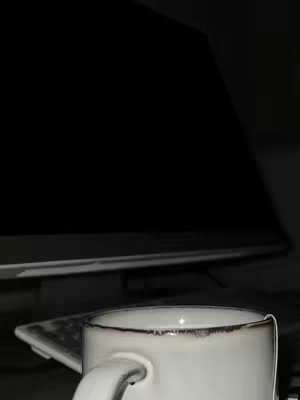 The cover image shows a close-up of a white coffee mug with a dark rim, and a computer monitor in the background. The mug is in sharp focus, and the rest of the background is subtly blurred, creating depth and emphasis on the cup. The scene suggests a workspace arrangement.