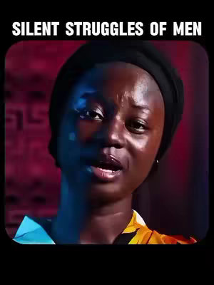 A close-up shot of a woman with dark skin, wearing a black head covering and a yellow-and-black patterned top. She appears to be speaking or reacting. The background is a blurred mix of red and pink hues, suggestive of a patterned fabric.