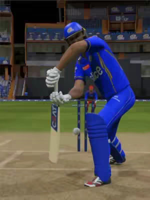 A screenshot from a cricket video game shows a batter in a blue and gold uniform in the middle of swinging the bat at a ball mid-air. The background shows the stadium with people in the stands and the wicket-keeper at the back.
