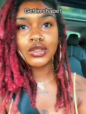 A selfie of a woman with red dreadlocks with 'Get in shape!' text overlayed. She has a nose ring, gold hoop earrings, and a gold necklace. She's in a car, and behind her is a dark interior; focusing on her lips and eyes, with the text at the top.