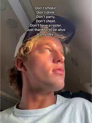 A young man with light skin and blonde hair, wearing a white t-shirt and a backwards navy baseball cap, is looking upwards towards soft natural light seemingly coming from a window. Text overlays on the top of the image contains a series of instructions.