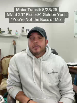 A man in a light gray hoodie and a black cap is speaking to the camera. The background includes a shelf with decorative items and a guitar. Text overlays at the top.