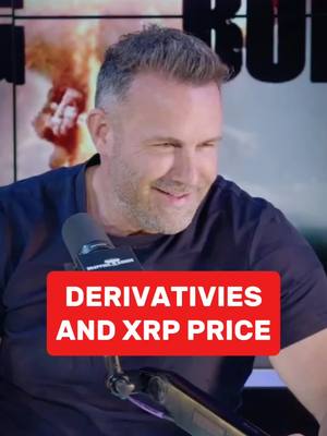 A man in a dark t-shirt with a microphone. A red rectangular box overlay with white text that says "DERIVATIVES AND XRP PRICE". In the background, there is a blurred explosion.