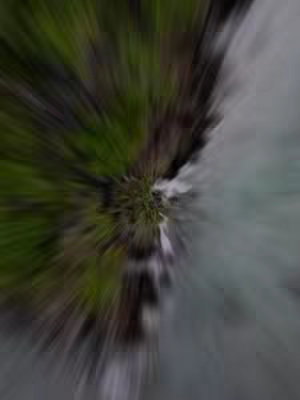 Abstract image with a central focus point with green elements on the left and gray to white elements on the right, showcasing a radial blur effect that suggests motion or energy.