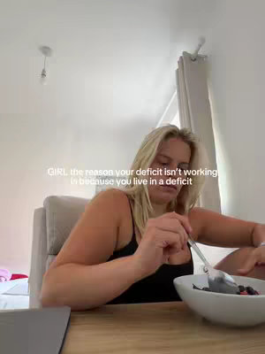 A woman with blonde hair is shown sitting at a wooden table, holding a spoon and approaching a bowl filled with food. Text overlays the image.