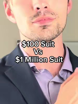 A close-up shot of a man from the chest up, with text overlayed. The man has short, dark hair and a light complexion and a slight smile. He is wearing a dark-colored blazer and a light purple collared shirt. The text overlay reads '$100 Suit Vs $1 Million Suit'. The background is blurred and indistinct.