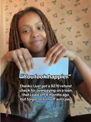 A woman with locs smiles, holding a white paper in front of herself, against a light gold wallpaper with a floral pattern. Text overlays on the image.