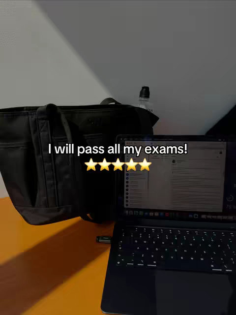 A laptop is open on an orange surface. A black bag and water bottle are to the left and behind the laptop. Text reading 'I will pass all my exams!' along with five gold stars is overlaid on the image.