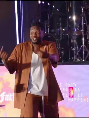 The video cover shows a man on a stage with a microphone, gesturing with his hands. The background features drums and stage lighting. The man is wearing brown suit and a white shirt.