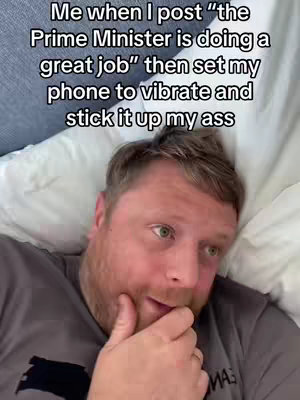 A man lies in bed, looking at the camera with his hand near his mouth. Text is added at the top.