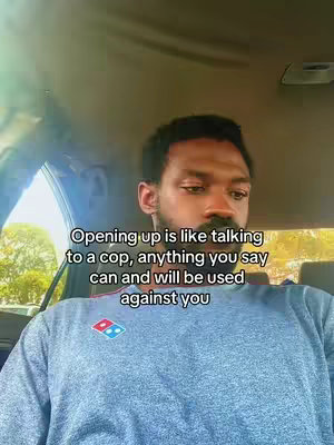 A man with a beard is seated in the driver's seat of a car, looking down with a contemplative expression. Text is overlaid, discussing the parallels between opening up and talking to law enforcement.