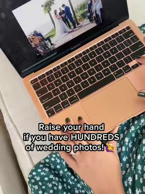 A person's hand, with painted nails and holding a laptop. The laptop displays a photo of a wedding scene on its screen. Text overlayed on top of the image includes questions about how many wedding pictures people may have.