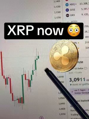 The image shows a computer screen displaying a cryptocurrency chart with an overlaid image of the XRP coin and a text overlay that reads 'XRP now' with an emoji. A pen is pointing towards the chart's data.
