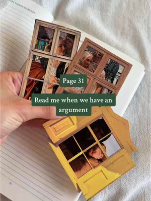 A hand holding a notebook open to a page. Three cut-out images of windows with pictures are arranged on the page. A text overlay reads: Page 31. Read me when we have an argument.
