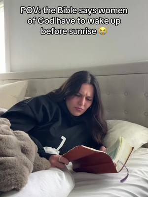 A woman is lying in bed, propped up against pillows, reading a Bible. The cover image has text overlay saying 'POV: the Bible says women of God have to wake up before sunrise' at the top.