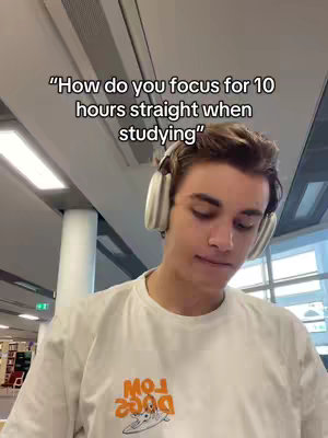 A young man wearing a white t-shirt and large headphones, looking down slightly in a well-lit environment with a blurred library or office setting as the background. Text overlayed at the top asks a question about focusing while studying.