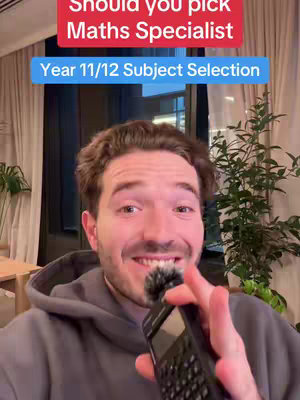 A man with brown hair and a partly visible stubbly beard looks at the camera, smiling. Above him reads text on red and blue color blocks. He is holding a small microphone in his hand.