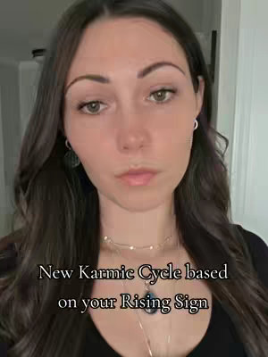 A woman with long, dark brown hair looks directly at the camera. The background is blurred, and the text overlay reads, "New Karmic Cycle based on your Rising Sign."