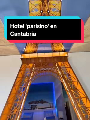 The image shows a view from the inside, looking up through the frame of a golden Eiffel Tower replica. Above, a blue ceiling fills the top of the frame, with the text overlayed on a black rectangle in the top left. Below the tower, there is a window depicting a painting of a landscape with a blue color theme.