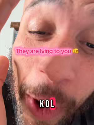 A close-up selfie focuses on the face of a man. The words "They are lying to you" are overlaid in pink, and below are the letters "KOL" inside a red rectangle over the man's mouth. The skin is pinkish, with visible pores and slight blemishes. The background is indistinct, suggesting an indoor setting with soft lighting.