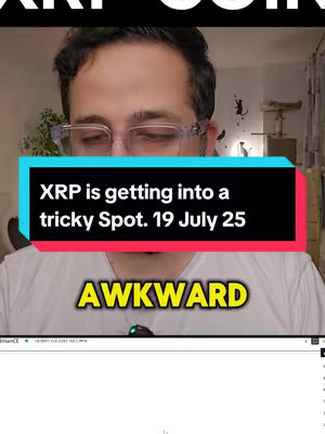 A man wearing glasses looks at the screen in a room. Overlaid on the screen is a red and blue box with white text that says, "XRP is getting into a tricky Spot. 19 July 25." Below this text is yellow text in a yellow box reading "AWKWARD". The background of the image includes part of a computer screen at the bottom, and in the background a cat tree, a window, and a curtain are visible.