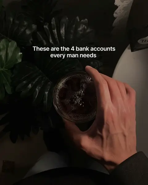 The image shows a hand holding a glass of a brown liquid, possibly coffee, with ice. The hand is positioned to the side, and the background consists of dark green leaves. Text overlaid on the image reads, "These are the 4 bank accounts every man needs."