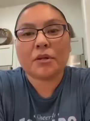A medium shot shows a woman with glasses looking directly at the camera. She has dark hair and is wearing a blue shirt. The background is out of focus, but appears to be an indoor setting. The overall tone of the image is straightforward and engaging.