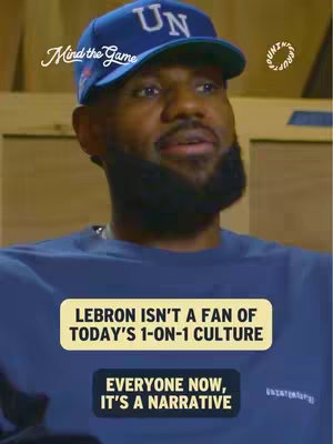 A medium shot shows a man, likely LeBron James, looking slightly upwards and to the side, wearing a blue baseball cap with 'UN' in white letters. Text overlays are placed over the image with a two-tone box. The background is blurred, suggesting an indoor setting.