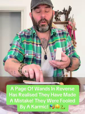A man in a green plaid shirt and a dark cap is holding a deck of cards and pointing his finger towards the cards on the table with a text overlay on the bottom.