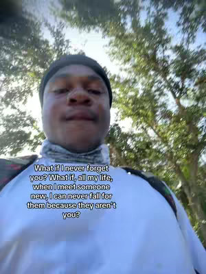 A selfie-style image with the creator in the foreground, wearing a black beanie and a white top. Text overlay is added at the bottom third. The background is blurred with green trees.