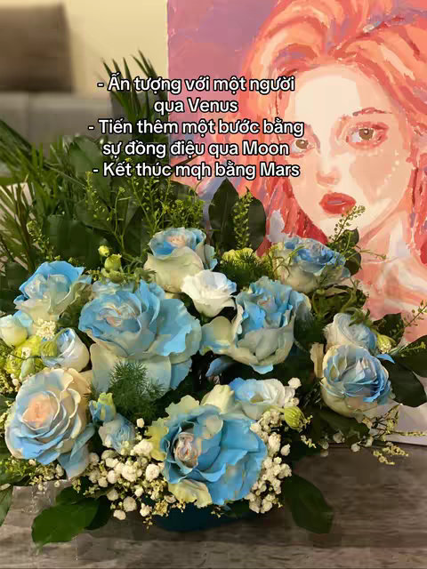 The image features a vibrant arrangement of light and dark turquoise roses with white accents, set against a soft background that includes a painted portrait of a woman with red-toned hair and a muted pink backdrop. Text overlays list astrological interpretations, and the composition is inviting and visually balanced.