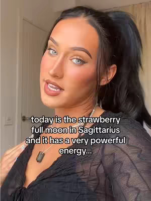 The cover image shows a woman with dark hair pulled into a ponytail, wearing a black top, and speaking directly to the camera with a neutral expression. Text overlayed on the image provides astrological detail.