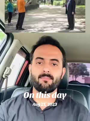 A man with a beard is inside a car, the upper part has a photo from outdoors with 3 people walking in a park, and a man in a suit standing in the distance. Overlayed on the image is text indicating the date.